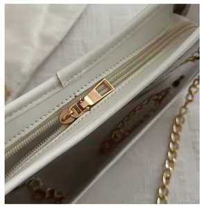 Detail of high-quality gold metal zipper and white leather edge on a clear PVC bag