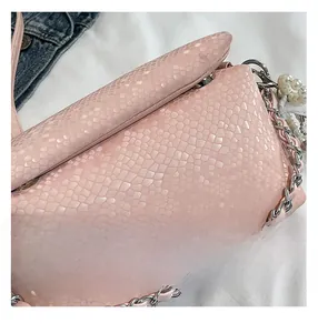 Gedetailleerde close-up van roze slangenleer textuur met zilveren ketting en parel