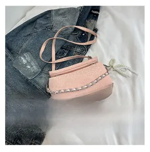 Detail van roze handtas met slangenprint en zilveren ketting op een denim achtergrond