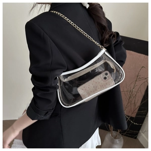 Detail view of transparent PVC shoulder bag with white trim and gold chain on a model