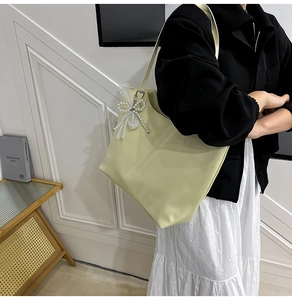 Detail van de lichtgroene tote bag met parelmoeren strik en kanten hanger, leerlook