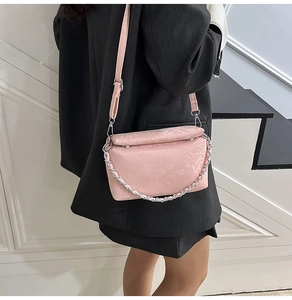 Detail van roze tas met slangenpatroon en zilveren ketting getoond op een model