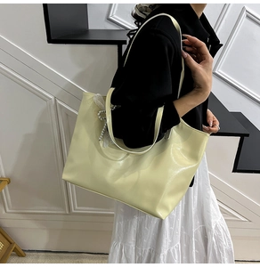 Detail van lichtgele shopper met witte kanten strik en parelhanger voor damesmode