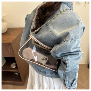 Detail of transparent PVC crossbody bag with pink trim and elegant golden chain strap