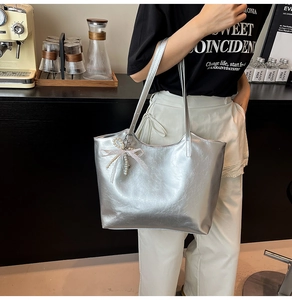 Zilveren metallic tote tas met roze kant strik en parelhanger gedragen over de schouder