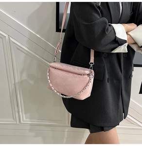Roze crossbodytas met slangenreliëf en zilveren ketting op zwarte blazer