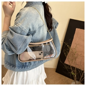 Detailed shot of transparent PVC baguette bag with gold chain strap on female model