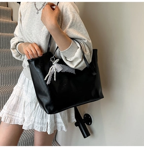 Detail van zwarte matleren shopper met witte kralen en kant strik hanger op model