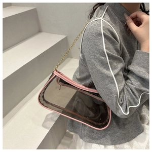 Detail der transparenten grauen PVC-Schultertasche mit rosa Lederbesatz und goldener Kette