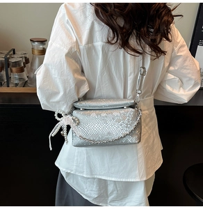 Detail van zilveren crossbodytas met slangenpatroon, parelstrik en metalen ketting