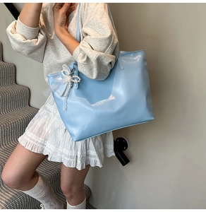 Detail van lichtblauwe glanzende tote bag met elegant parel- en kantstrikje als hanger