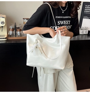 Detail van de witte lederen tote bag met een hanger van kant, parels en een hart
