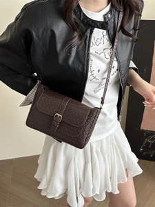 Retro dark brown woven baguette bag with gold buckle worn by model in a stylish look