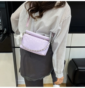 Detail van lavendelkleurige crossbodytas met slangenmotief en zilveren ketting