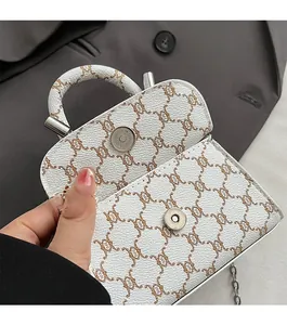 Detail of white litchi leather mini bag showing metal magnetic closure and silver chain