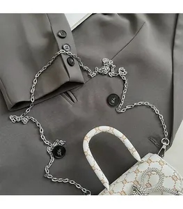 Close-up of white mini bow handbag with monogram pattern and sparkling rhinestones