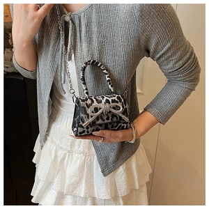Detail of mini leopard print handbag featuring a sparkling rhinestone bow and chain strap
