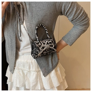 Detail view of mini leopard print handbag with sparkling rhinestone bow and chain strap