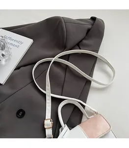 Detail showing the adjustable white shoulder strap and metal hardware of the small square bag