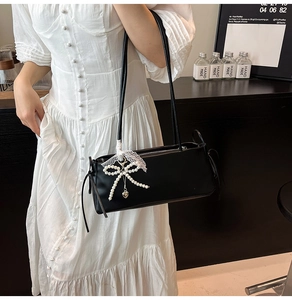 Detail van zwarte leren tas met parels, kanten lint en metalen hart hanger