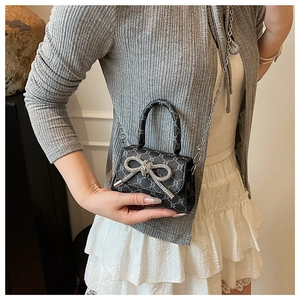 Detailed view of mini crossbody bag with crystal bow and vintage monogram pattern
