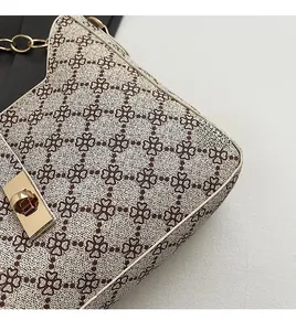 Detail of beige shoulder bag with geometric print and gold metal rectangle clasp closure