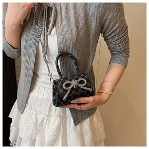 Close-up of mini bow handbag featuring monogram pattern and sparkling rhinestone detail