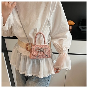 Detailed shot of mini pink logo crossbody bag with rhinestone bow and silver chain
