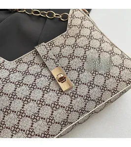 Detailed view of the gold rectangular twist lock and printed fabric texture of the handbag