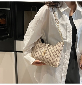 Detail of floral pattern on beige shoulder bag with gold chain strap and metal clasp