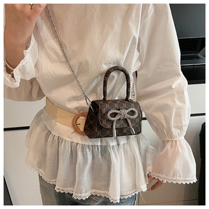 Detail of mini crossbody bag with a large rhinestone bow and metallic chain strap