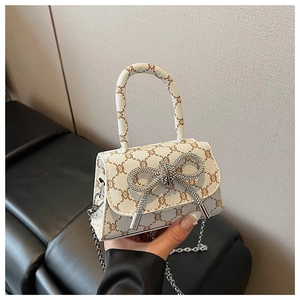 Detail of white mini crossbody bag with crystal bow and metallic chain strap