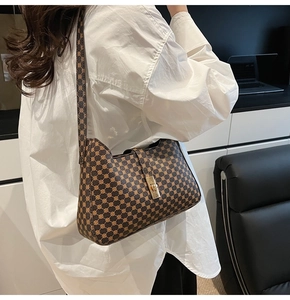 Brown printed underarm bag with gold metal twist lock shown on model with white shirt