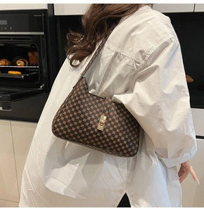 Detail of vintage patterned shoulder bag with gold twist lock on a white shirt background
