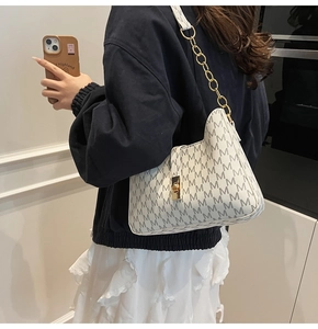 Detail of white monogram shoulder bag featuring golden metal chain and twist lock clasp