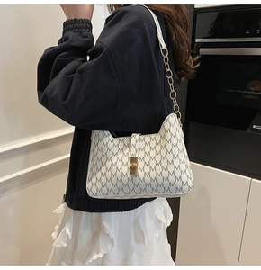 Detail of vintage M-print shoulder bag with gold chain strap and metal clasp closure