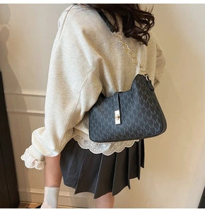 Close-up of black vintage patterned shoulder bag with gold chain strap and metal clasp