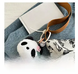 Dettaglio di un ciondolo a forma di panda in peluche su borsa tote in tela retrò