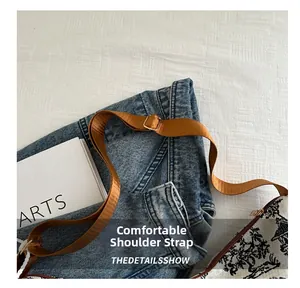 Dettaglio della tracolla regolabile in nylon marrone e borsa in tela jacquard con stampa