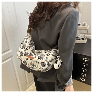 Detail of vintage canvas crescent bag with black pattern and panda plush charm