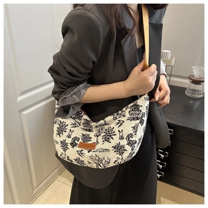 Detail of embroidered beige half-moon bag featuring vintage landscape patterns and leather tag