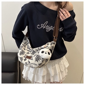Detail of canvas crescent bag featuring vintage embroidery and plush panda charm