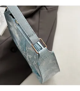 Dettaglio borsa a tracolla azzurra floreale con hardware metallico dorato e zip rifinita