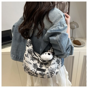 Detail of canvas shoulder bag with panda plush pendant shown in a bright home setting