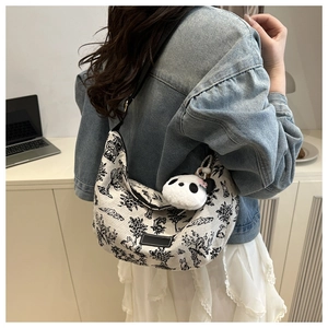 Hobo bag with floral print and panda pendant worn over the shoulder in a minimalist setting