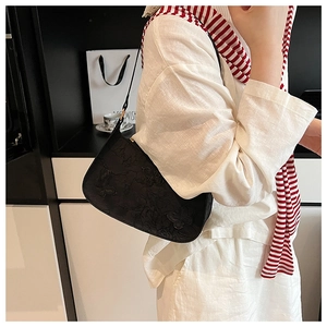 Détail du sac sous l'aisselle noir avec gaufrage 3D papillon et floral sur la surface