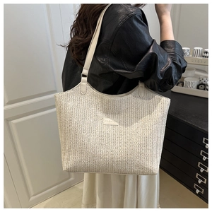 Detailed close-up of woven herringbone texture and FASHION label on beige tote bag