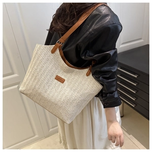 Detail of hand-woven beige tote bag with brown leather straps and fashion patch