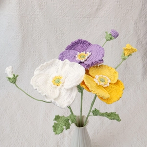 Detail of handmade crocheted poppy bouquet with yellow, white and purple flowers in a vase