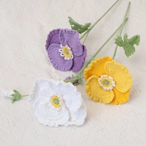 Handmade crochet poppy bouquet with purple yellow and white flowers on white fabric